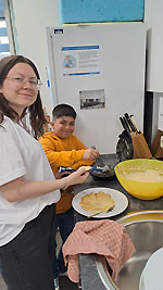 Abdullah und die Projektmitarbeiterin Hannah Baunacher backen gemeinsam Waffeln für die Gäste.