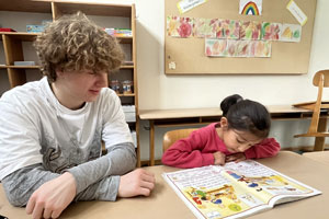 Lesepate Noah Wagenhäuser übt mit seinem Patenkind Rozarin das Lesen (Foto: Christina Raithel/MGH)