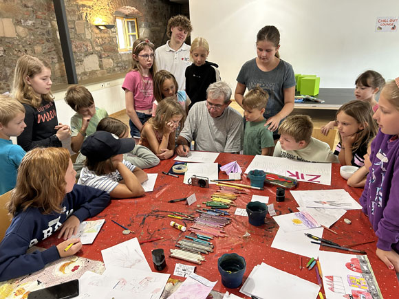 Wie male ich einen Löwen? Kunsttherapeut Andreas Neunhoeffer zeigt den Kindern eine bestimmte Technik zum Malen von Tieren. (Foto: Friederike Schulz / MGH)